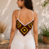 Back view of a young woman wearing the Boho Chic Crochet Halter Top featuring a colorful granny-square crochet pattern, shoulder straps, and white fringe detailing.