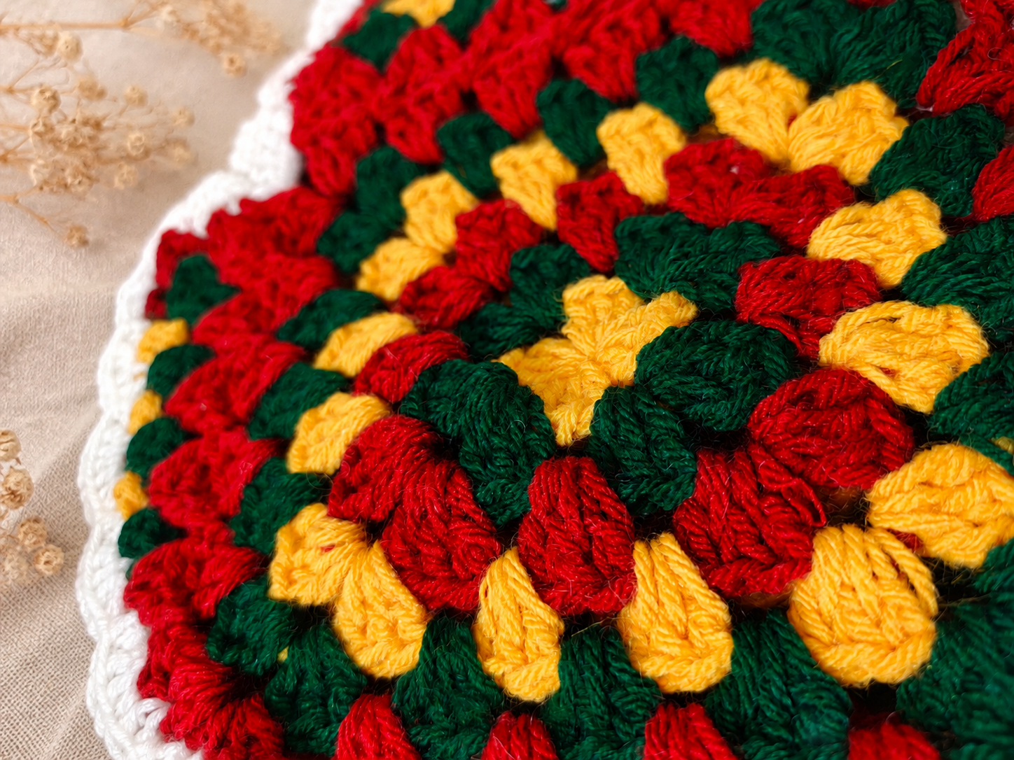 Close-up of the handmade granny square crochet pattern on the Boho Chic Crochet Halter Top, featuring red, green and yellow cotton yarn with intricate textured stitches.