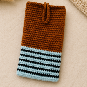 Rustic Loops crochet phone pouch in brown, light blue, and black stripes, displayed on a soft neutral background