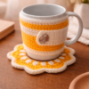 Handmade crochet mug cozy and coaster set in yellow and white on a warm wooden table with soft cozy background