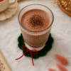 Ribbed glass filled with hot chocolate placed on a handmade green crochet coaster with red bow detailing, styled with cozy table props.